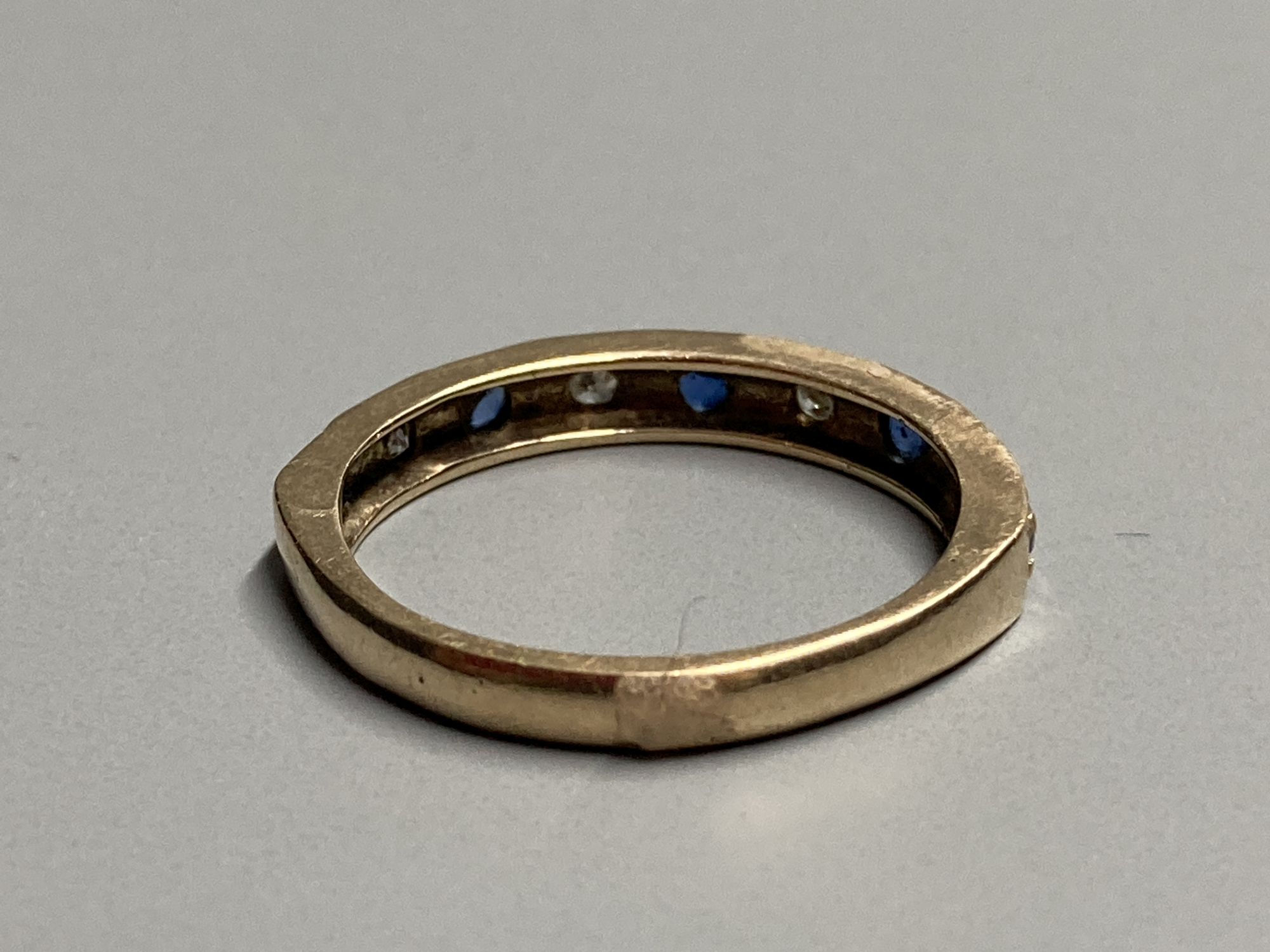 A modern 9ct gold, sapphire and diamond set nine stone half hoop ring, size L, gross 2.3 grams.